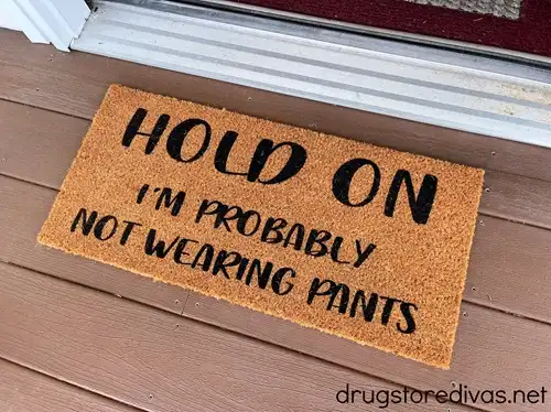 A doormat that says Hold On I'm Probably Not Wearing Pants in front of a door.