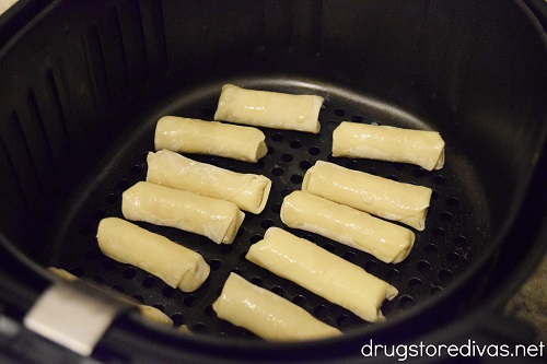 Ten wonton mozzarella sticks in an air fryer.