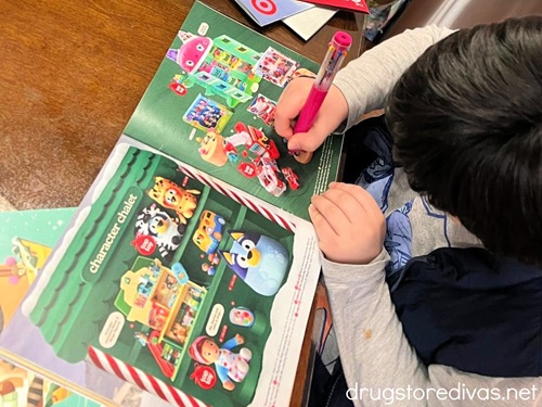 A little boy circling pictures in a holiday wish book.
