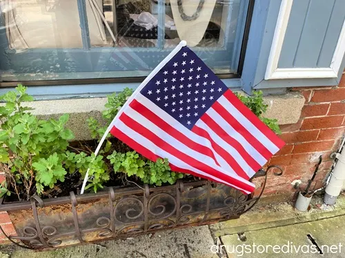 An American flag in a planter in front of a blue window.