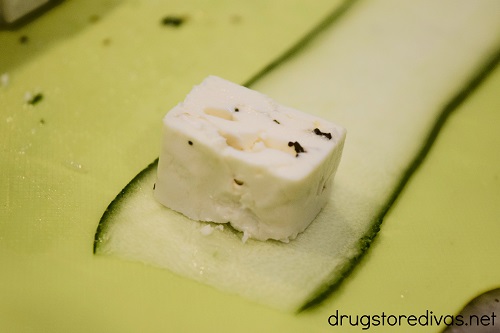 A cube of feta on top of a slice of zucchini.