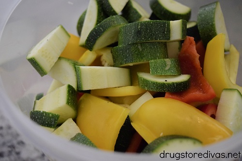 Onion, yellow pepper, red pepper, and zucchini cut in a bowl.