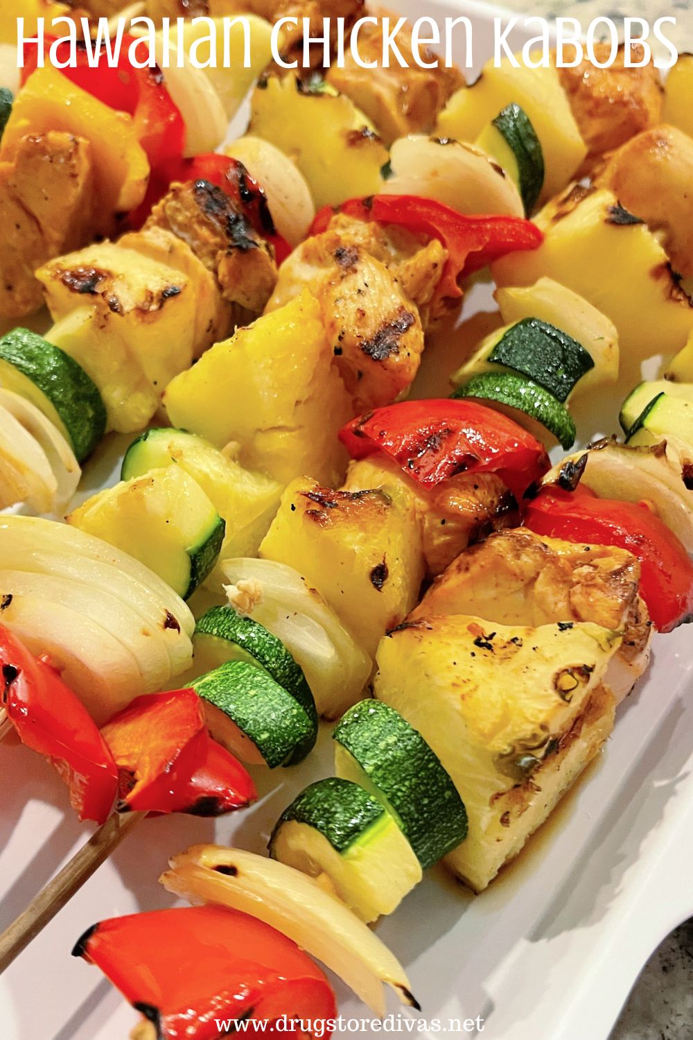 A bunch of skewers with vegetables and chicken on a white tray with the words 
