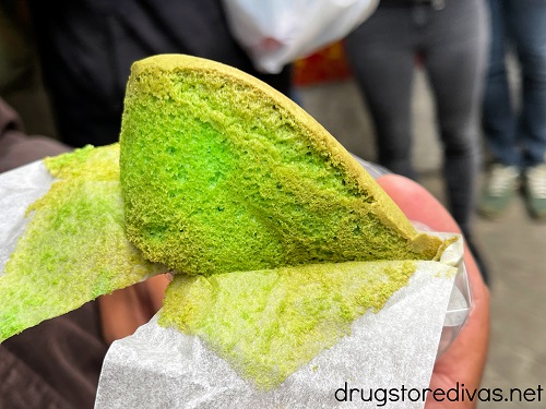 A hand holding a green sponge cake.