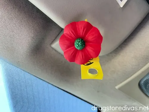 A red poppy hanging off a car's visor.