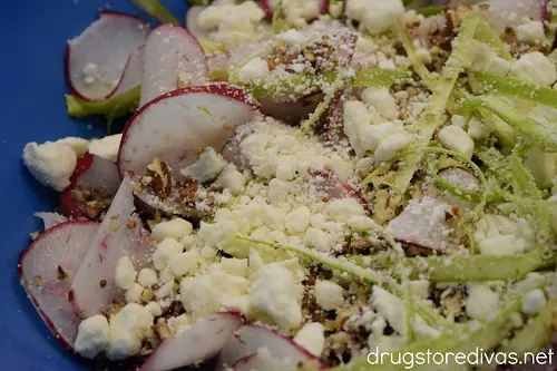 Shaved asparagus, shaved radish, pecans, and feta in a blue bowl.