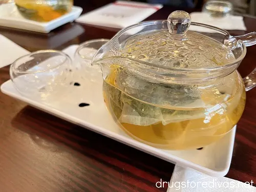 A tea pot with tea on a white tray.