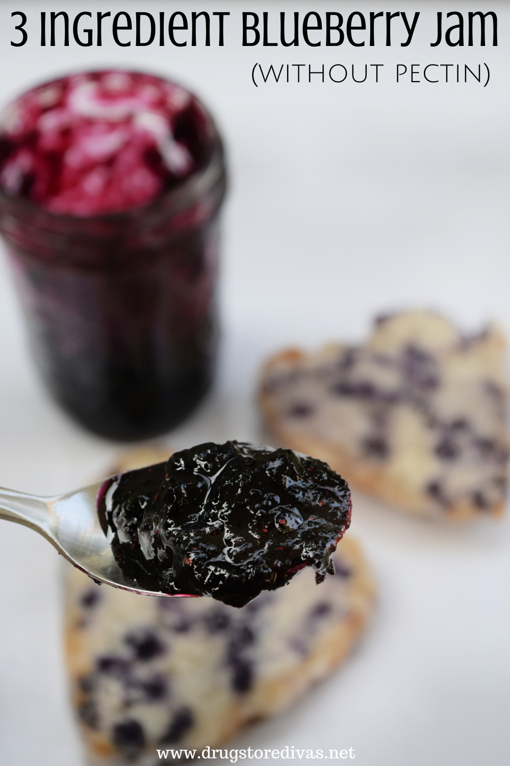 A jar of dark purple jelly, a blueberry biscuit cut in half, and a spoon of that jelly hovering over in the forefront with the words 