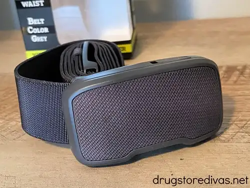 A belt with a speaker on the front on a table with a box in the back.