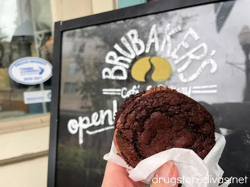 A hand holding a chocolate fudge pie in front of a Brubaker's sign in Sumter, South Carolina.