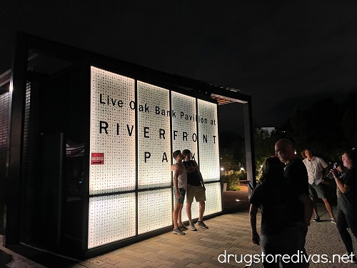 Two women getting their photo taken in front of a sign at Live Oak Bank Pavilion at Riverfront Park in Wilmington, NC.