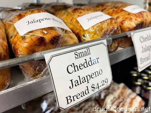 Homemade bread on a shelf at Swartzentruber's Bakery in Abbevilel, SC with the words "Small Cheddar Jalapeno Bread $4.29" on a sign in front of it.