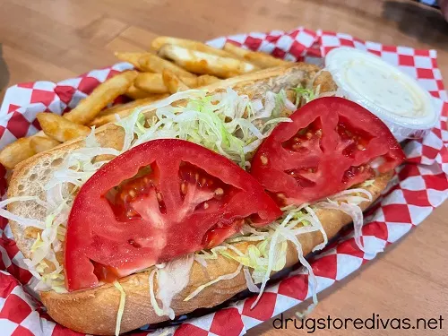 A hoagie with tomato and lettuce with fries in the back, from Theo's Deli in Abbeville, SC.