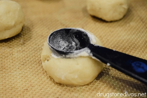 A measuring spoon being pushed into a cookie dough ball.