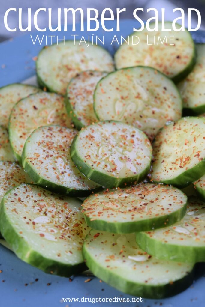 Cucumbers on a blue plate with red seasoning on top and the words "Cucumber Salad (with Tajin and Lime)" digitally written above them.