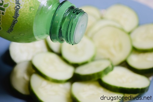 Lime juice being poured on cucumber slices.