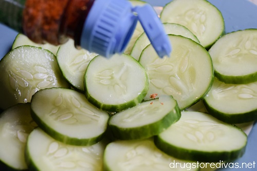 Tajin seasoning being sprinkled on cucumber slices.
