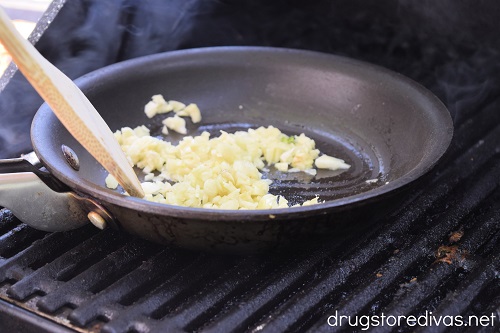 Chopped garlic and oil in a pan on a grill.