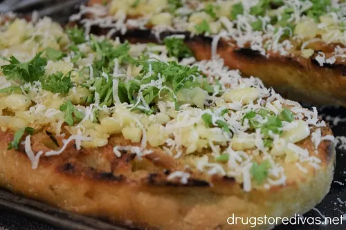 Cheese, parsley, and chopped garlic on top of bread.