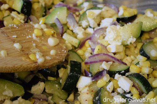 Mexican Corn and Zucchini Salad with queso fresco being stirred with a spoon.