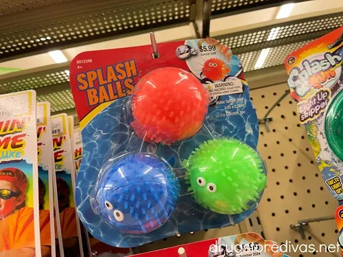 A pack of three splash balls (one orange, one blue, and one green) in a pack on a hook in a store.