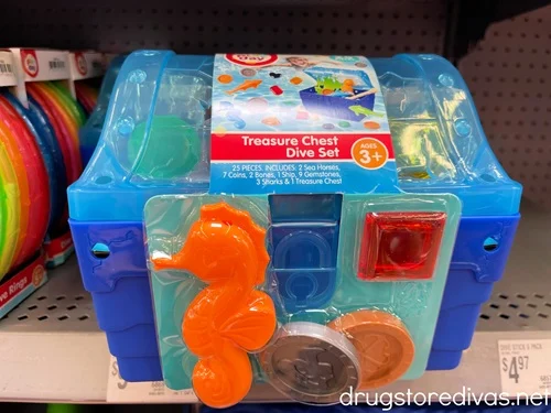A treasure box dive toy with coins and a seahorse in a package on a store shelf.
