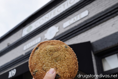 A hand holding a cookie in front of TLC Confections in Edgefield, SC.