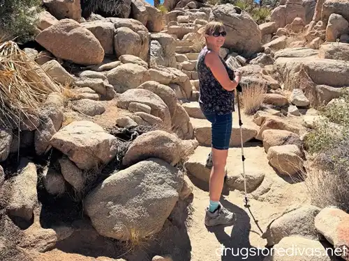 A woman hiking through rocks using a trekking pole.