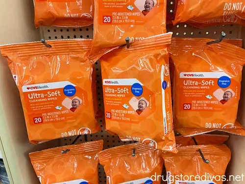 Orange packs of baby wipes on pegs in a store.