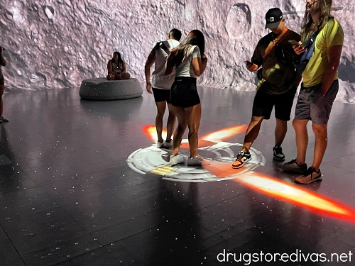 People stepping on a projection of a rocket and flames coming out at the Illuminarium Las Vegas.