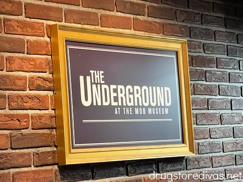A framed sign on a brick wall that says The Underground at The Mob Museum.