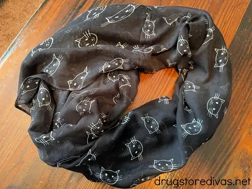 A black scarf with white cartoon cats on it.