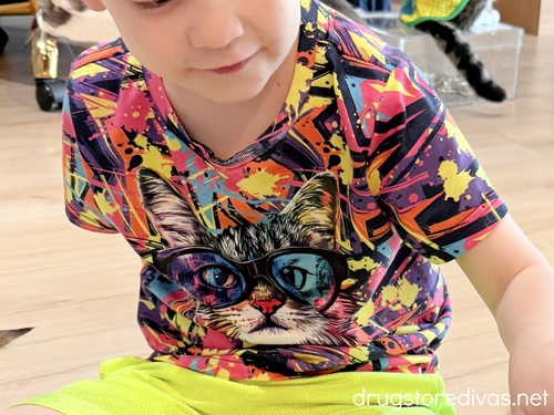A boy in a neon shirt with a cat on it.