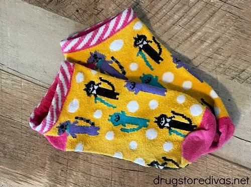 A pair of orange socks with white polka dots and cats on them.