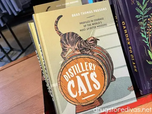 A few copies of a book called Distillery Cats on a shelf in a store.
