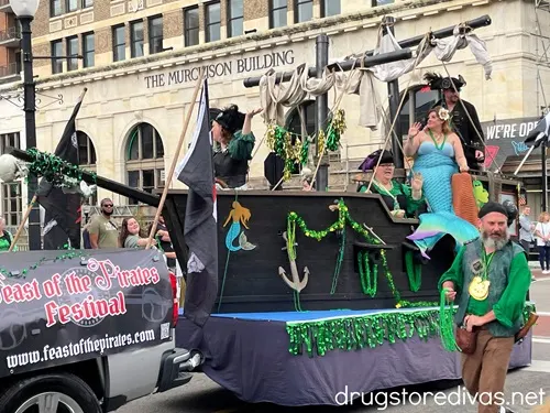 A pirate ship decorated for St Patrick's Day in a parade with a banner advertising the Feast of The Pirates in Belville, NC.