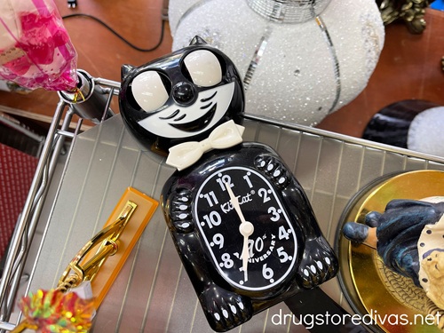 A black cat clock surrounded by other vintage items in a store.