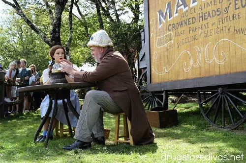 Dorothy and Professor Marvel sitting at a table, looking at a crystal ball, at the Land Of Oz theme park.