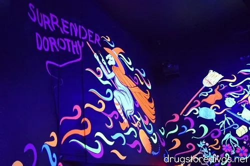A blacklight room with a witch on the wall and the words Surrender Dorothy in the Land Of Oz theme park.