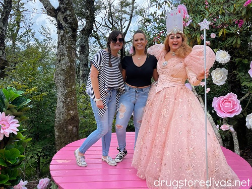 Three women, one who is dressed like Glinda the Good Witch from the Wizard of Oz at the Land of Oz theme park.