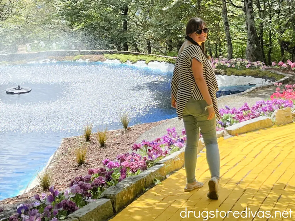 A woman walking on the Yellow Brick Road, next to a pond, at the Land Of Oz theme park.
