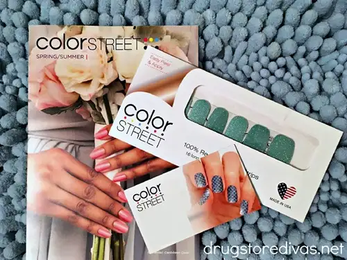 A pack of colorstreet nail  polish strips with a catalog and business card on a blue background.
