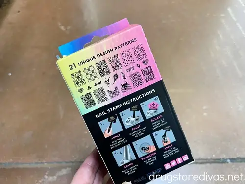 A hand holding a package of nail stamps.