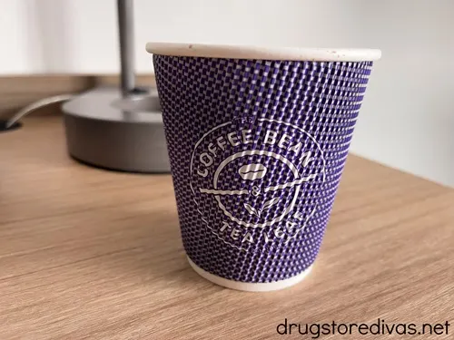 A purple cup on a table that says the Coffee Bean & Tea Leaf on it.