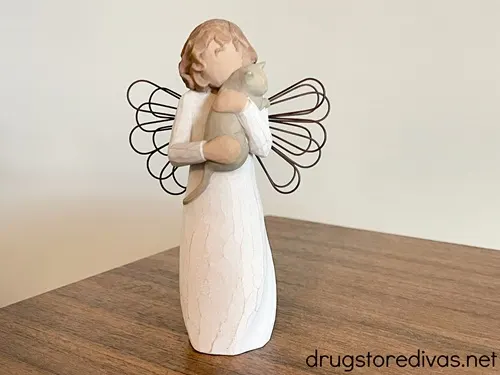 A Willow Tree angel holding a cat figurine.
