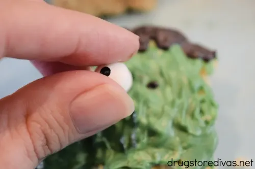 Candy eyes being placed on a Rice Krispy Treat that looks like Frankenstein.