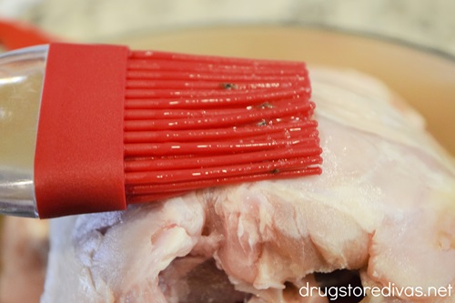 A pastry brush being used on a turkey breast.