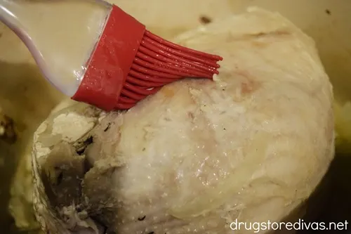 A pastry brush being used on a turkey breast.