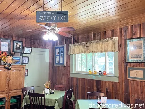 A sign that says "Entering Avery Co." above tables in a restaurant.