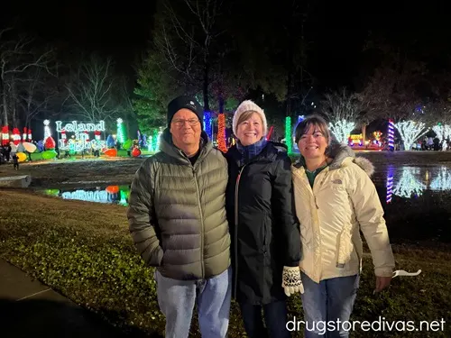 A man and two women, all in jackets and two in hats, in front of Christmas lights at Leland in Lights in Leland, NC.